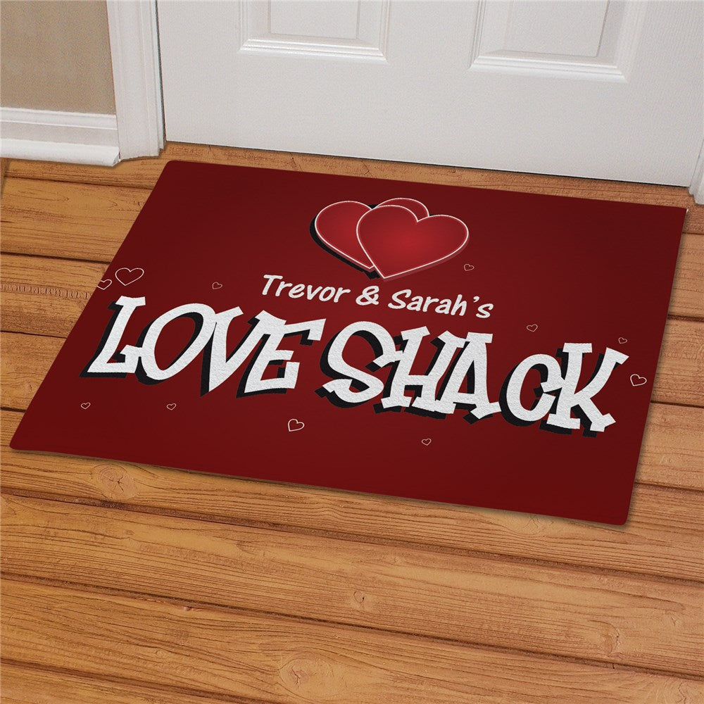 Doormat with 'Trevor & Sarah's LOVE SHACK' text and heart design on a wooden floor.