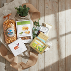 Assorted snacks and treats on a wooden surface with a plant and burlap ribbon.
