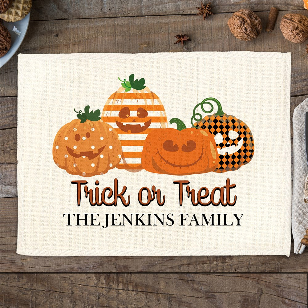 Halloween-themed placemat with pumpkins and 'Trick or Treat THE JENKINS FAMILY' text on a wooden surface.