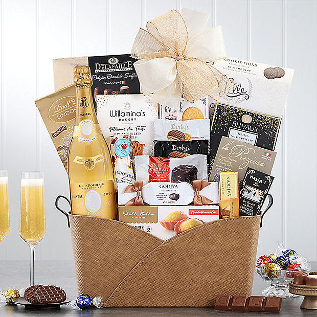 Gourmet gift basket with champagne, cookies, and other snacks on a white background